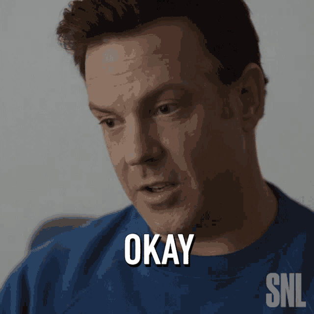 a man in a blue shirt says okay in white letters