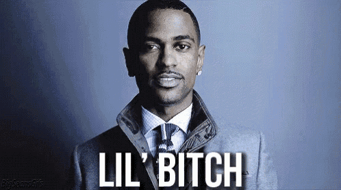 a man in a suit and tie is standing in front of a blue background and saying `` lil bitch '' .