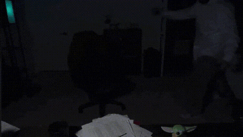a person standing in a dark room with a stuffed animal on a table