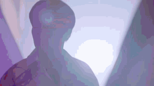 a silhouette of a man 's head is visible in a purple light