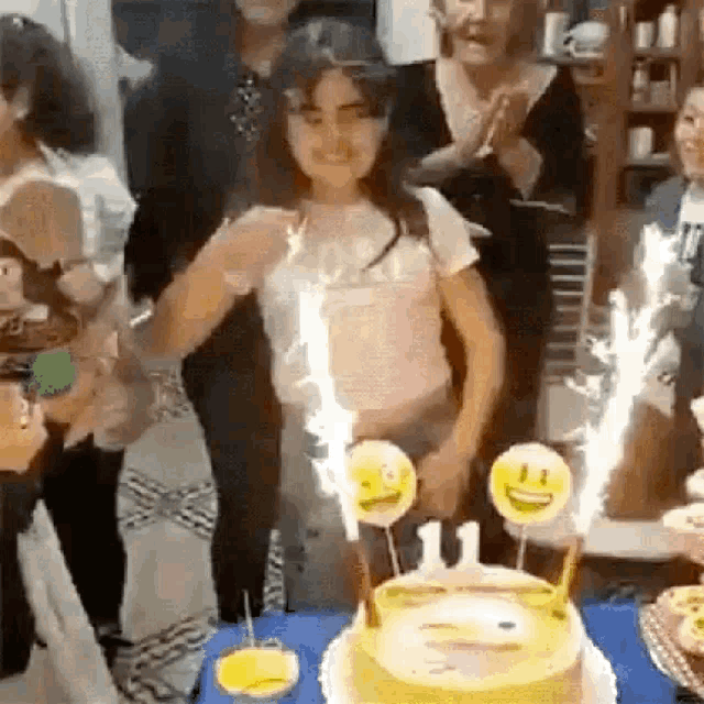 a girl is blowing out candles on a birthday cake with smiley faces on it .