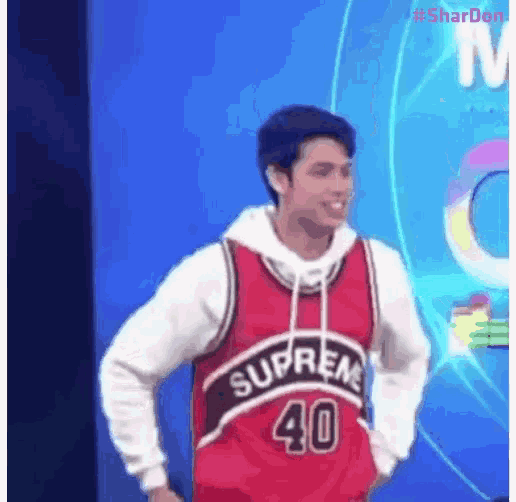 a man wearing a red supreme basketball jersey is standing on a stage .