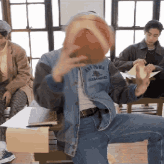 a man in a denim jacket has a basketball on his face