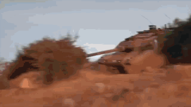 a tank is driving down a dirt road in the desert .