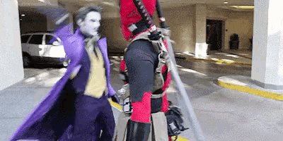 a man in a purple coat is standing next to a man in a red costume .