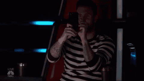 a man in a striped shirt is taking a picture of himself with a cell phone