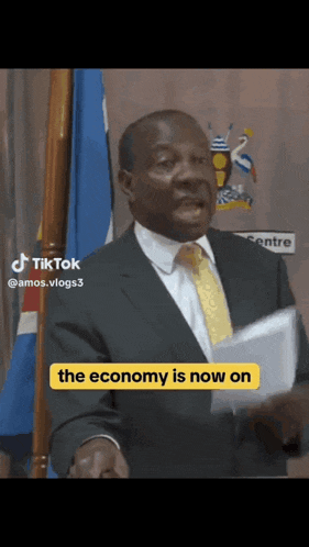 a man in a suit and tie is giving a speech and the economy is now on