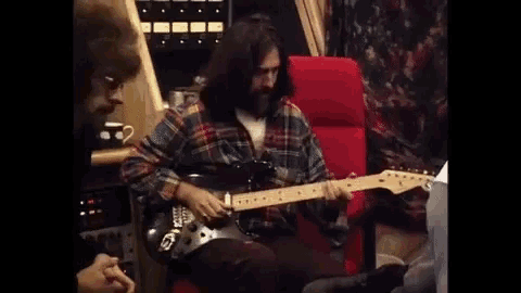 a man is sitting in a chair playing an electric guitar .