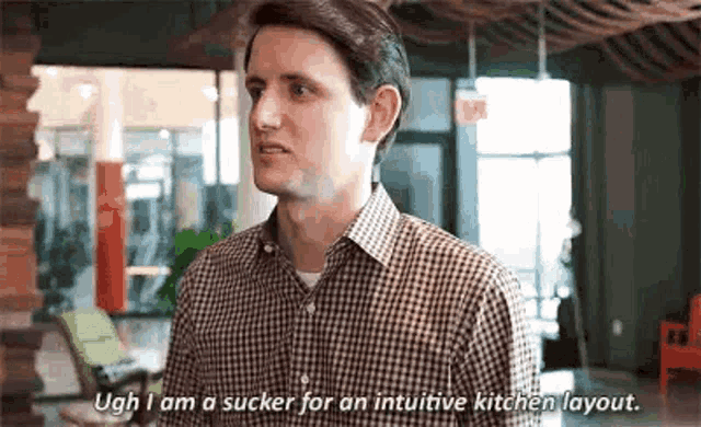 a man in a plaid shirt is standing in a room and talking to another man .