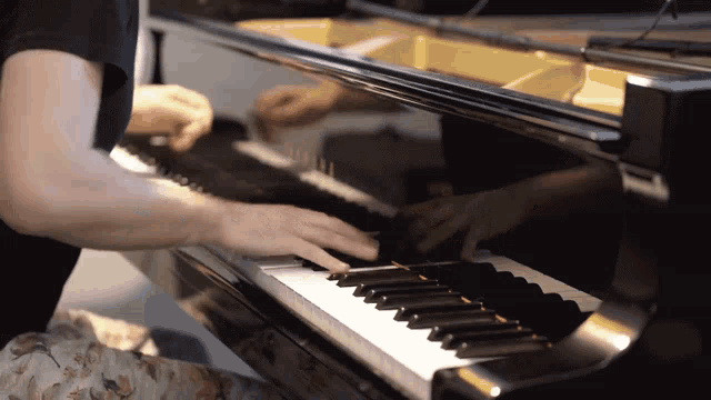 a person playing a piano with a reflection of a person in the piano