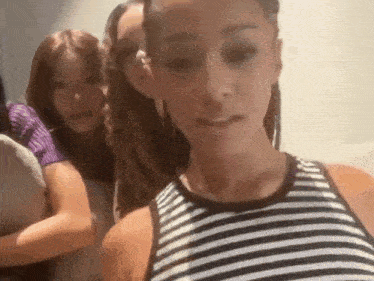 a woman wearing a striped tank top is standing next to two other women .
