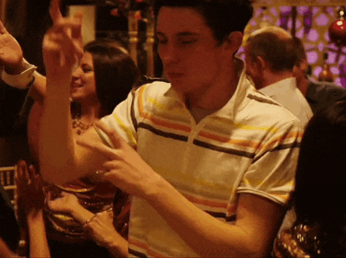a man in a striped shirt is dancing in a crowded room