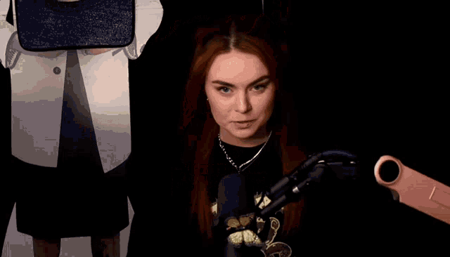 a woman with red hair is wearing a black shirt that says tidy .