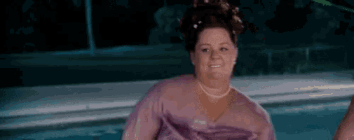 a woman in a purple dress is standing in front of a swimming pool .