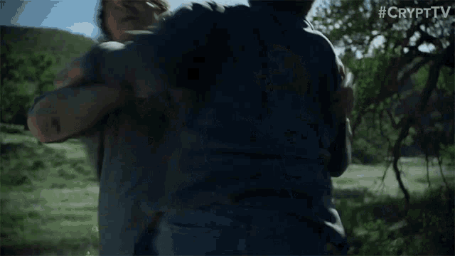 two men are fighting in a field and one of them is holding the other in his arms .