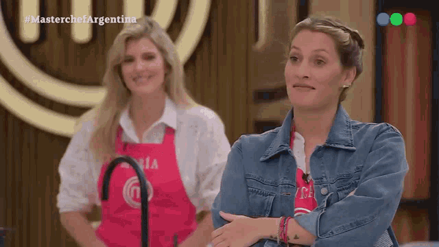 two women are standing in front of a sign that says masterchef argentina on it