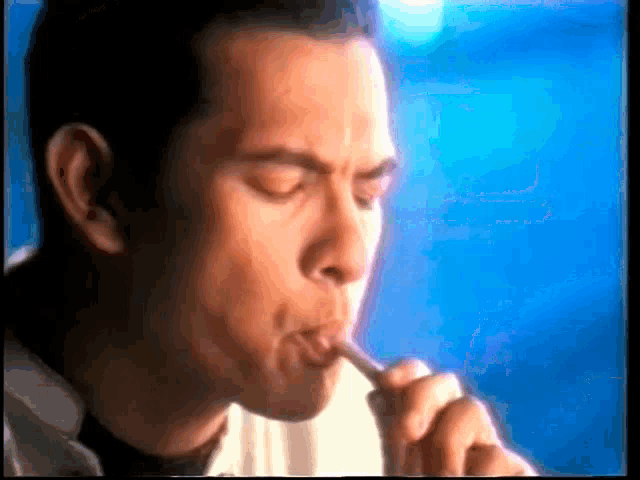a man is brushing his teeth with a blue background