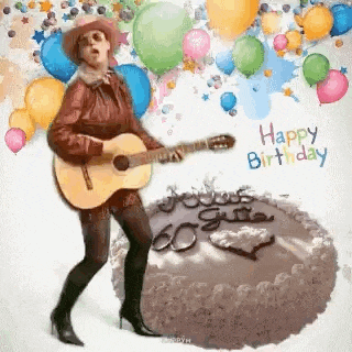 a woman is holding a guitar in front of a birthday cake .