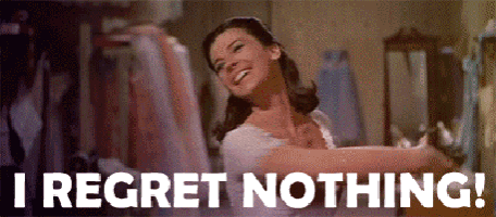 a woman in a white dress is dancing in a room with the words `` i regret nothing '' written below her .