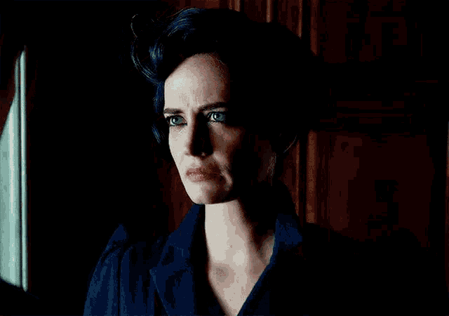 a woman with blue hair is standing in front of a window looking out .