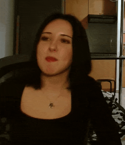 a woman wearing a black shirt and a necklace with a pendant