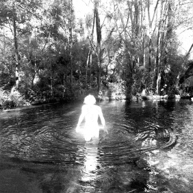 a black and white photo of a naked person in a river