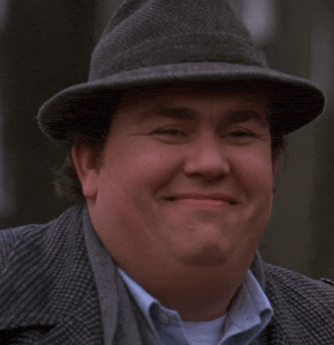 a man wearing a hat and a suit is smiling for the camera