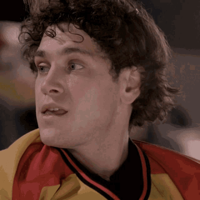 a close up of a man wearing a yellow and red jersey
