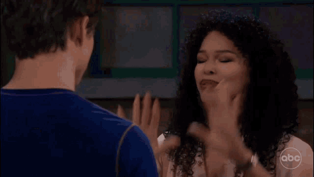a man and a woman are standing next to each other and the woman is waving her hands at the man .
