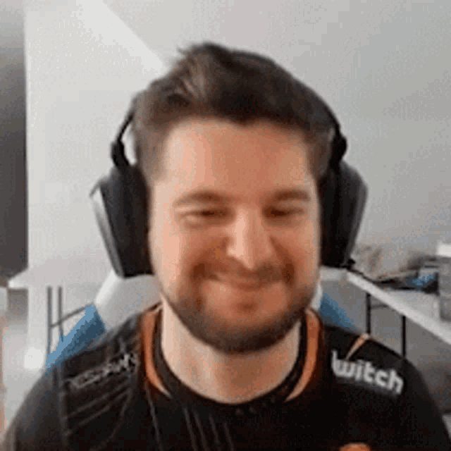 a man with a beard is wearing headphones and a twitch shirt .