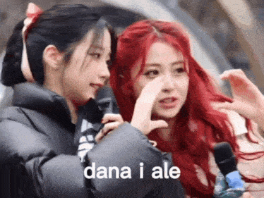 two girls with red hair are standing next to each other and one is covering her nose with her hand .