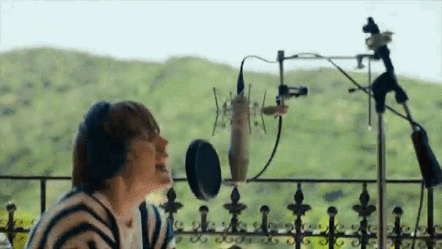 a woman is singing into a microphone on a balcony while wearing headphones .