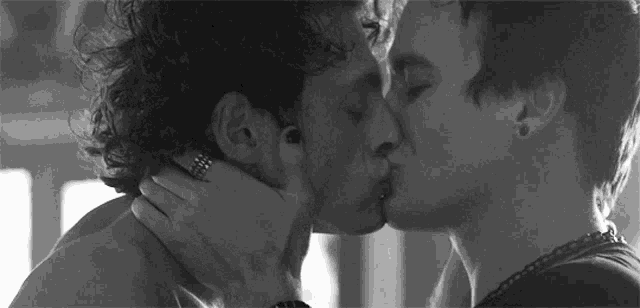 a black and white photo of two men kissing .