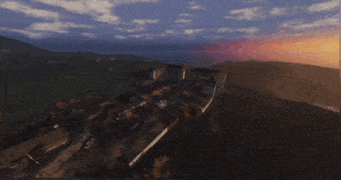 an aerial view of a large building on top of a hill at sunset