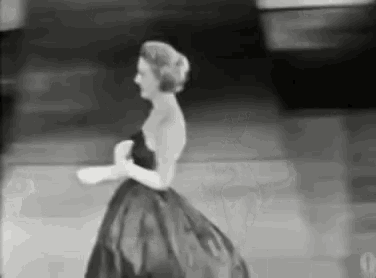 a woman in a long black dress is walking down stairs .