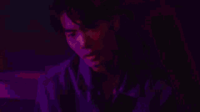 a man is singing into a microphone in a dark room