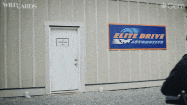 a sign for elite drive automotive hangs on a building