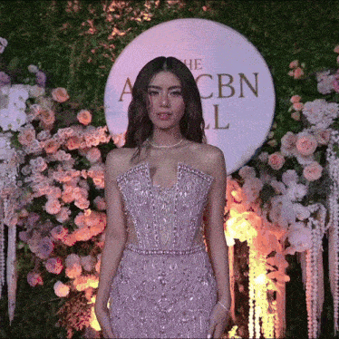 a woman in a purple dress is standing in front of a cbn logo