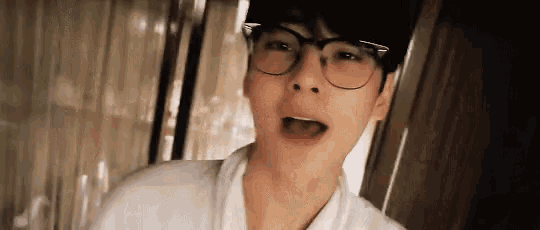 a close up of a man wearing glasses and a white shirt .
