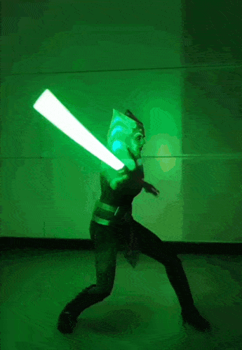 a woman in a star wars costume is holding two lightsabers