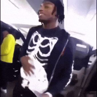 a man wearing a skeleton shirt is holding a white object .