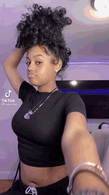 a woman in a black crop top is taking a selfie .