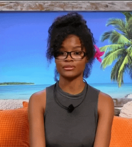 a woman wearing glasses is sitting on a couch in front of a beach scene