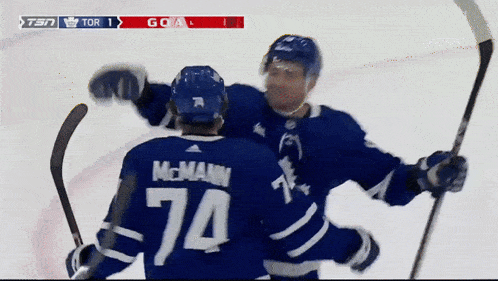 a hockey player with the number 74 on his jersey is hugging another player