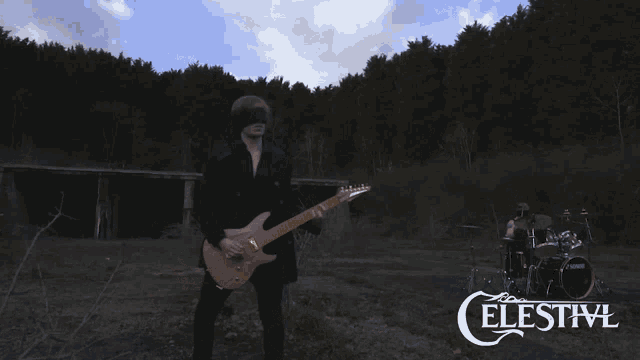 a man playing a guitar in front of celestivl drums
