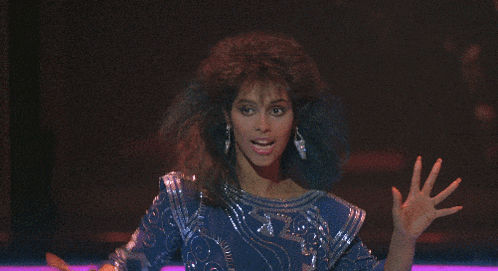 a woman in a blue sequined top and silver earrings is dancing