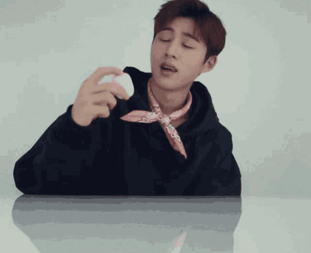 a man wearing a black hoodie and a pink scarf holds a pink object