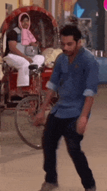 a man is dancing in front of a rickshaw while a man sits in a chair .