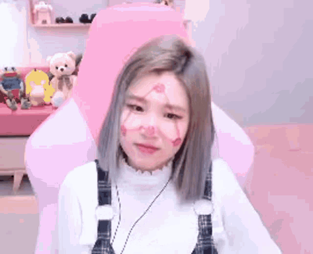 a woman is sitting in a pink chair with her face painted pink .