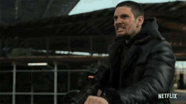 a man in a black leather jacket is holding a gun with netflix written on the bottom